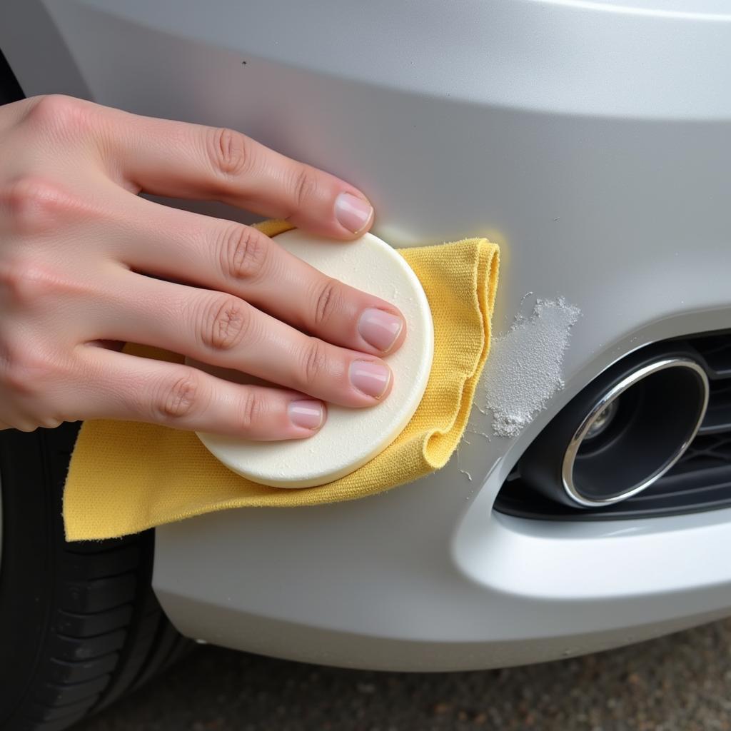 Applying rubbing compound to a scratched car bumper