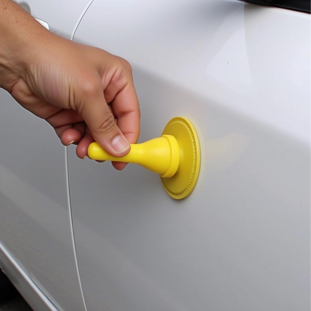 Fixing a small car door dent with a suction cup