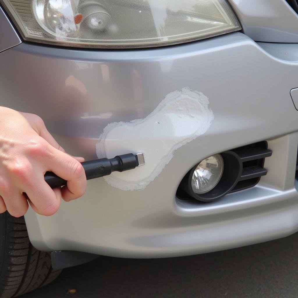 Applying putty to fix a deep scratch on a car bumper