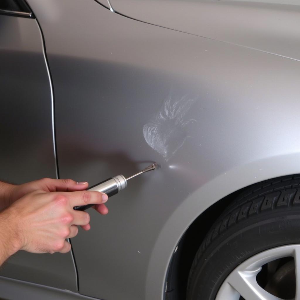 Technician performing PDR on a car door